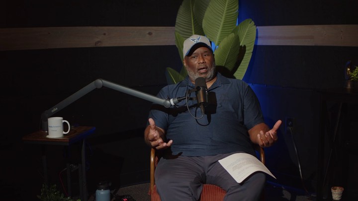 A closer camera angle of a participant speaking into a microphone in Podcast Room B