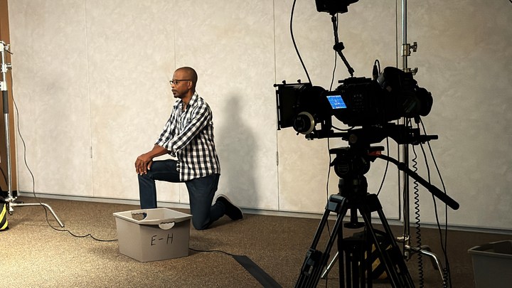 A participant rehearsing in front of a camera and backdrop
