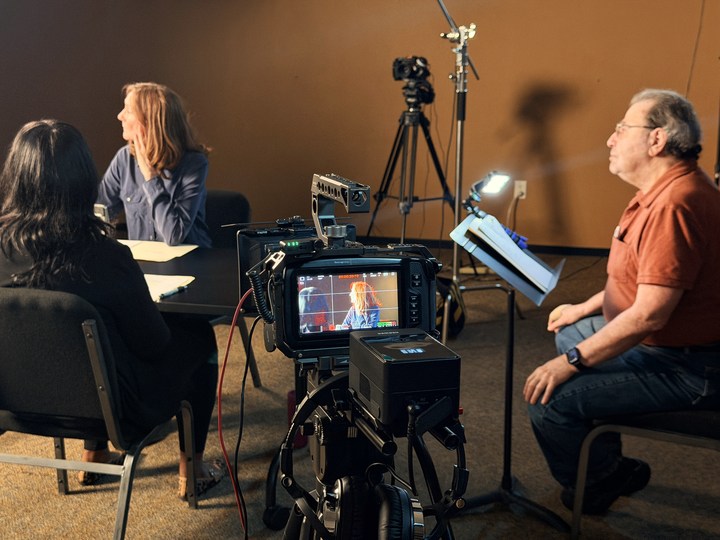 Participants at the table with a recording camera in the foreground