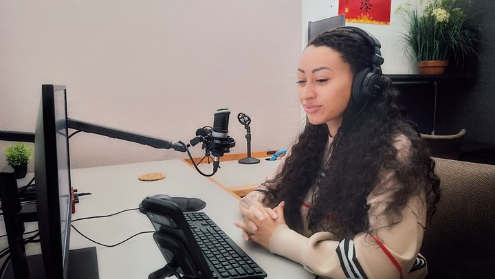A person seated with headphones at the microphone in Podcast Room A
